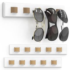 three pairs of sunglasses hanging on the wall with pegs to hold them in place