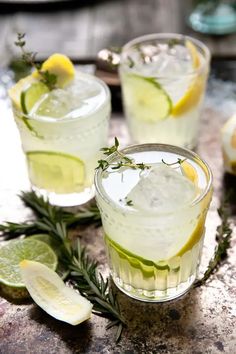 two glasses filled with lemonade and gin cocktail next to sliced limes on a table