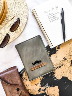 a notebook with a mustache on it next to sunglasses and other items that include a map