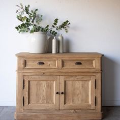 a wooden cabinet with two vases on top