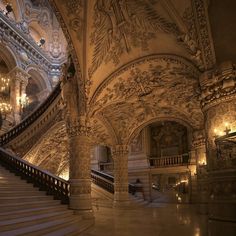 an ornate staircase with chandeliers and paintings on the walls in a large building