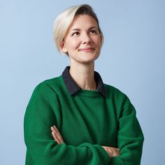 a woman in a green sweater with her arms crossed and looking up at the camera