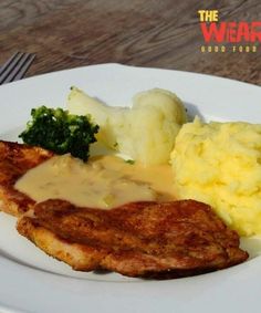 a white plate topped with meat and potatoes covered in gravy next to broccoli