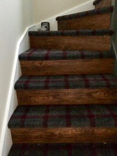 the stairs are made of wood and have plaid carpet on them, but no one is going down