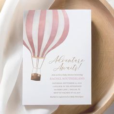 a pink and white striped hot air balloon baby shower is displayed on a wooden plate