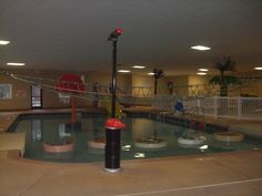 an indoor swimming pool with slides and water features in the middle, surrounded by concrete flooring