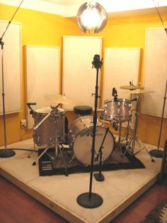 a drum set up in the middle of a room with two microphones on each side