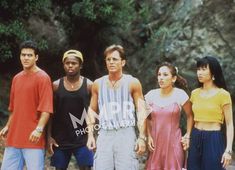 a group of young people standing next to each other in front of some rocks and trees