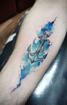 an anchor tattoo on the arm with blue watercolor paint splattered over it