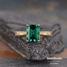 an emerald colored ring sitting on top of a rock