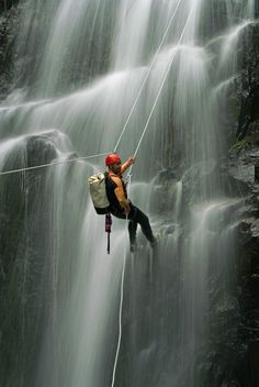 a man is rapping in front of a waterfall