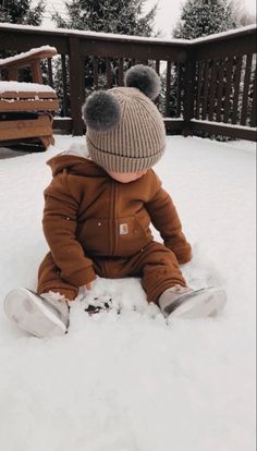 a baby sitting in the snow wearing a hat