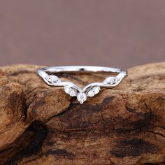 a white gold ring with three diamonds on top of a tree branch in front of a brown background