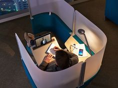 a man sitting at a desk with a laptop computer and cell phone in his hand