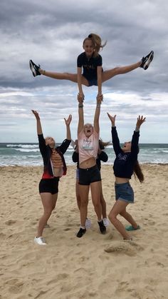 four girls are doing tricks on the beach with their hands in the air and one girl is balancing