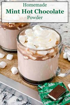 two mugs filled with hot chocolate and marshmallows on a cutting board