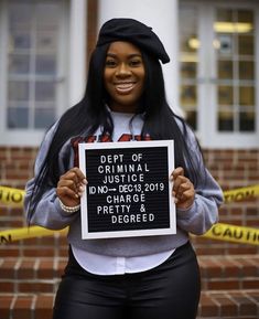 a woman holding up a sign in front of a brick building with caution tape around her