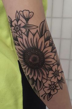 a woman's arm with a sunflower and flowers tattoo on the left arm