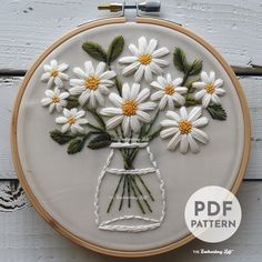 the embroidery pattern has daisies in a mason jar