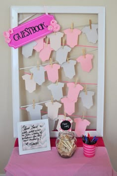 a pink and white display with clothes hanging on the clothes line next to a cup full of pencils