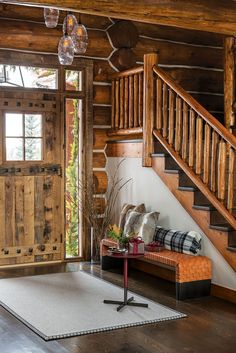 a living room filled with furniture next to a stair case and wooden railing on the wall