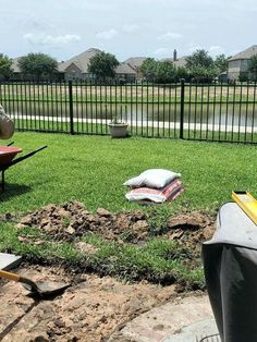 a yard with lawn furniture and tools laying on the ground in front of a fence