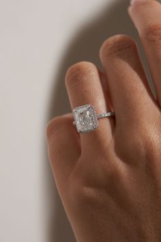 a woman's hand with a diamond ring on top of her finger, showing the center stone