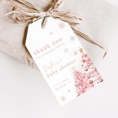 a gift wrapped in brown paper with a pink christmas tree tag on it's side