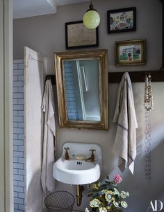 a bathroom sink sitting under a mirror next to a wall mounted faucet and towel rack