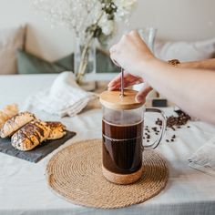 a person is holding a straw in front of a cup of coffee and pastries