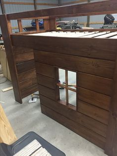 a loft bed made out of wood in a garage with the roof partially down and windows open