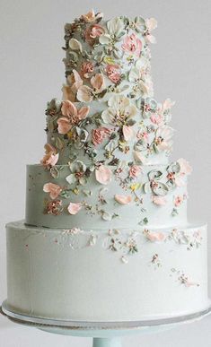 a three tiered white cake with flowers on top and a red button in the middle