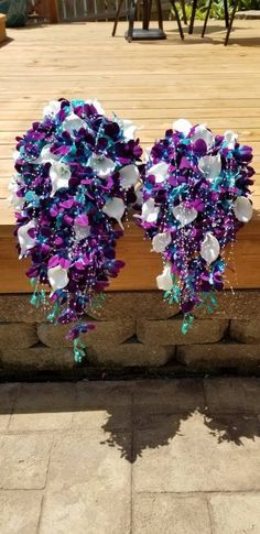 two purple and white flowers are hanging from the side of a wooden deck