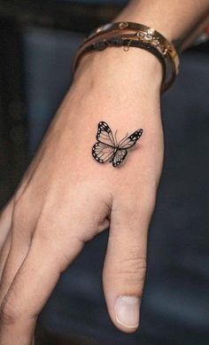 a small butterfly tattoo on the left hand