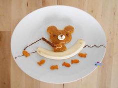 a white plate topped with a teddy bear on top of a banana and peanut butter