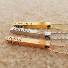 three personalized necklaces are laying on the carpet