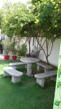 a concrete picnic table and benches in the grass