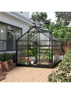 a small greenhouse sitting on top of a wooden deck next to a building with windows