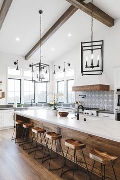 a large kitchen island with four stools in front of it and an open floor plan