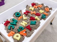 a child's sand tray with letters and numbers in it