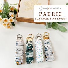 four fabric keychains sitting on top of a table next to flowers and a box