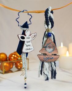 two christmas ornaments hanging from a rope on a table with candles and decorations in the background