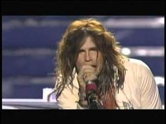 a man with long hair is singing into a microphone