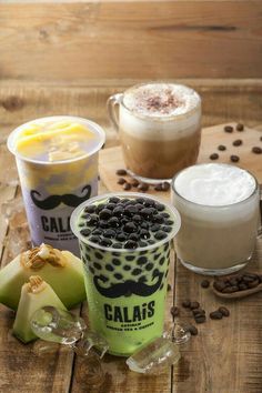 three different types of beverages on a wooden table with coffee beans, milk and fruit