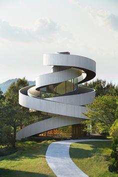 a white spiral shaped building with trees in the background