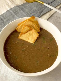 a white bowl filled with black bean soup and tortilla chips