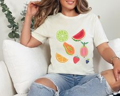 Indulge in a burst of fruity fun with our vibrant fruit collage t-shirt! Perfect for those who love a pop of color and a touch of whimsy in their wardrobe. Whether you're strolling through the farmer's market or catching up with friends over brunch, this tee adds a juicy twist to any outfit. How to Order *Select color and size  Shipping & Production Time *Free Shipping, 4-11 business days Product Details  *This classic unisex jersey short sleeve tee fits like a well-loved favorite. These t-shirt White Casual Top With Fruit Design, Casual White Tops With Fruit Design, Casual White Top With Fruit Design, Trendy Multicolor Fruit Print Top, Trendy Multicolor Tops With Fruit Print, Fun White T-shirt With Fruit Print, Fruit Design Graphic Tee With Crew Neck, Crew Neck Fruit Design Graphic Tee, Crew Neck Graphic Tee With Fruit Design