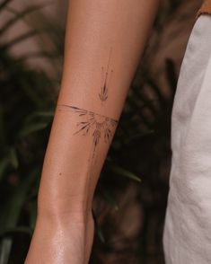 a woman's arm with a tattoo on it and a plant in the background