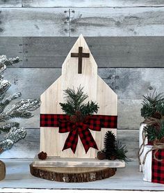 a wooden house with a red and black bow on it, surrounded by christmas trees