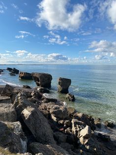 some rocks and water under a cloudy blue sky